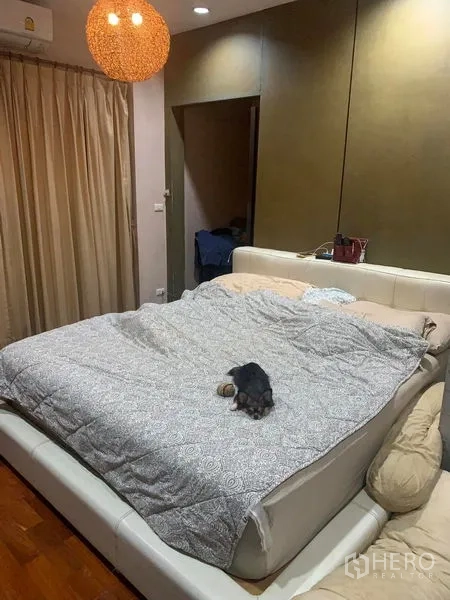 独立式住宅 出租在Prawet, Bangkok - 主卧配大床、吊灯与落地窗帘。