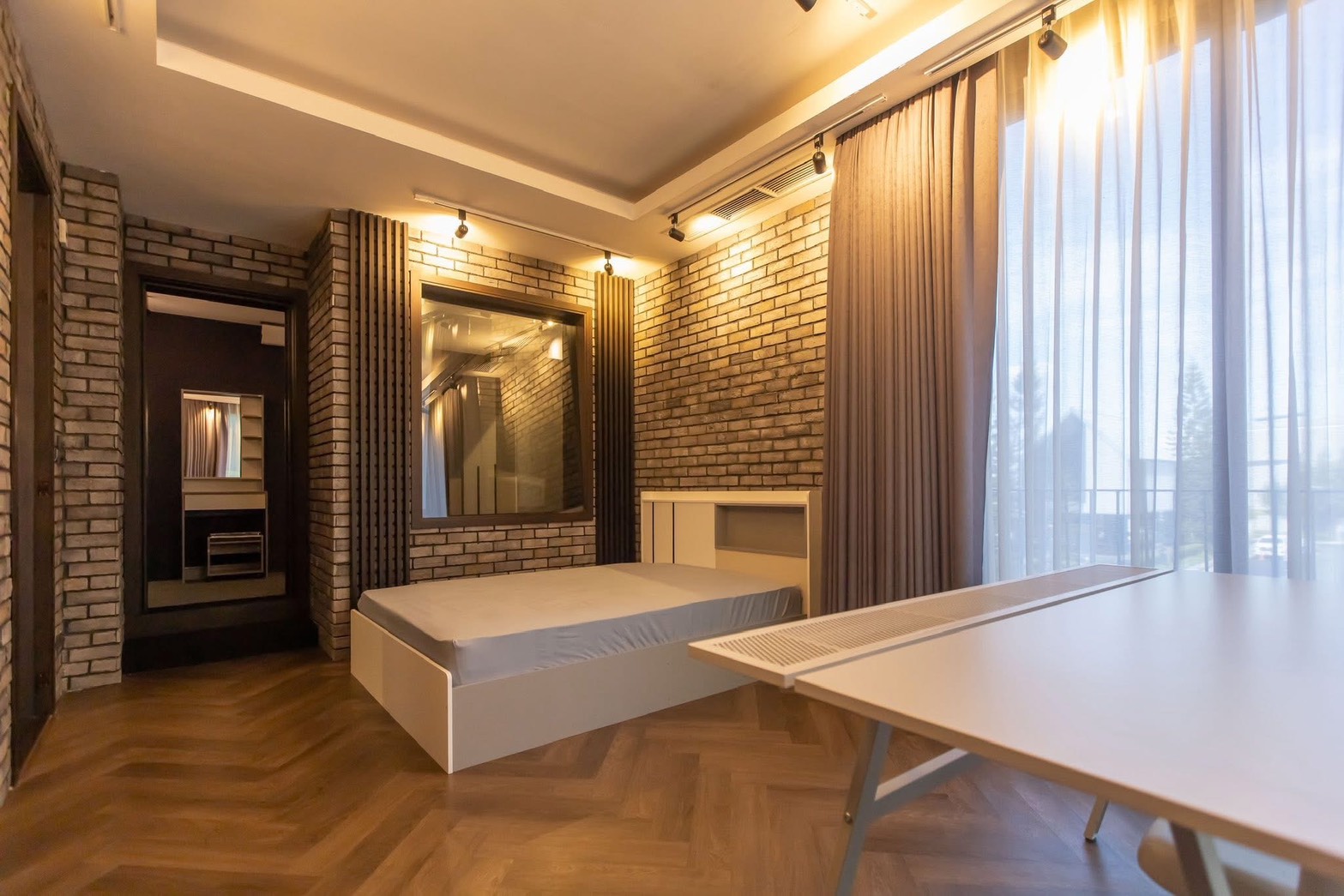 独立式住宅 出租在Lat Phrao, Bangkok - 温馨卧室，裸砖特色墙，平台床，人字形木地板与纱帘。