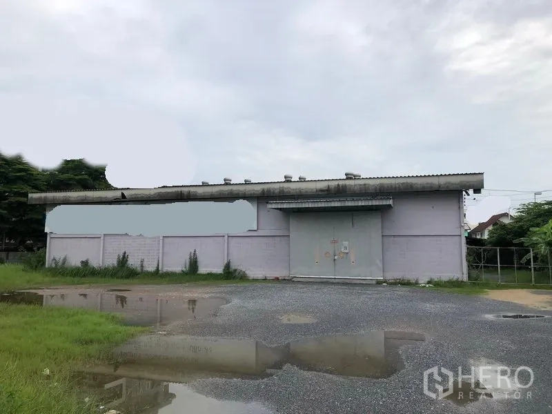 คลังสินค้า ให้เช่าในBang Kapi, Bangkok - ภายนอกโกดังชั้นเดียว ประตูเหล็กบานใหญ่ ลานจอดและทางรถลูกรัง