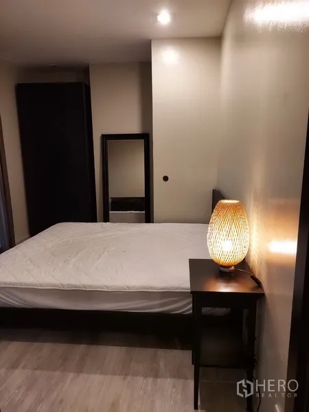 คอนโด ให้เช่าในPhaya Thai, Bangkok - ห้องนอนอบอุ่น โต๊ะข้างเตียงโคมไฟหวาย กระจกและพื้นลายไม้