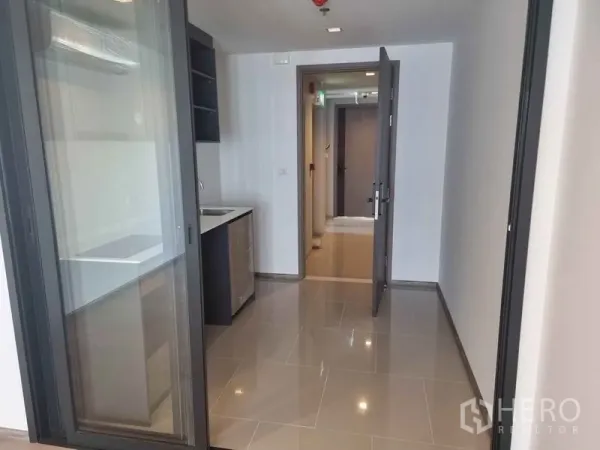 Condominium for sale in Phaya Thai, Bangkok - Compact kitchen with sliding glass door, built-in sink and glossy tiled floor.