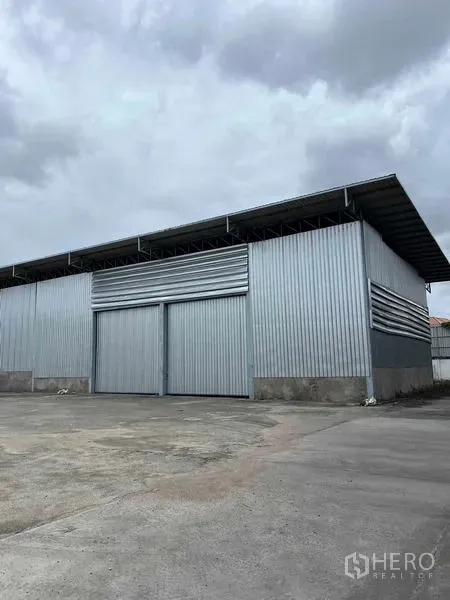คลังสินค้า ให้เช่าในMueang Chon Buri, Chon Buri - โกดังผนังเมทัลชีท หลังคาทรงจั่วสูง ประตูบานสไลด์คู่ บนลานคอนกรีตกว้าง.