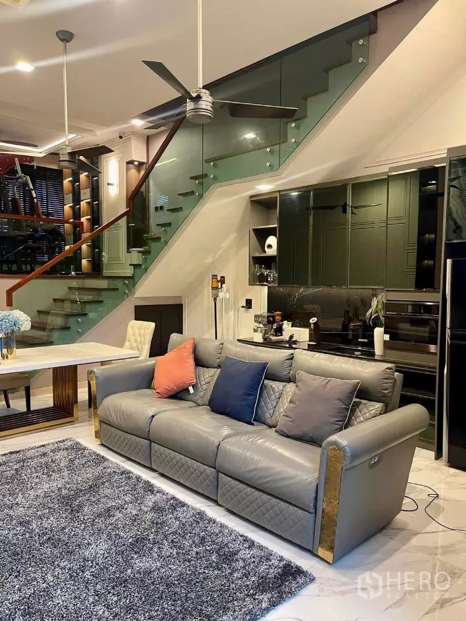 ทาวน์เฮาส์ ให้เช่าในChatuchak, Bangkok - พื้นที่นั่งเล่นกว้าง โซฟาหนังสีเทา บันไดราวกระจก และครัวสมัยใหม่