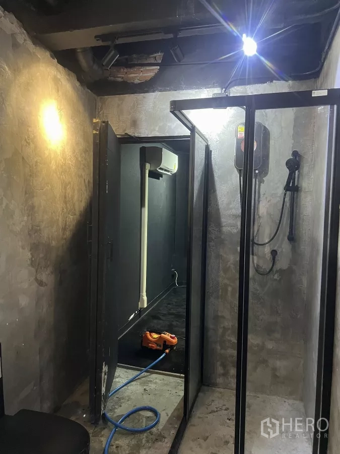 Home Office for rent in Wang Thonglang, Bangkok - Industrial bathroom with concrete walls, glass shower enclosure, and wall-mounted water heater.