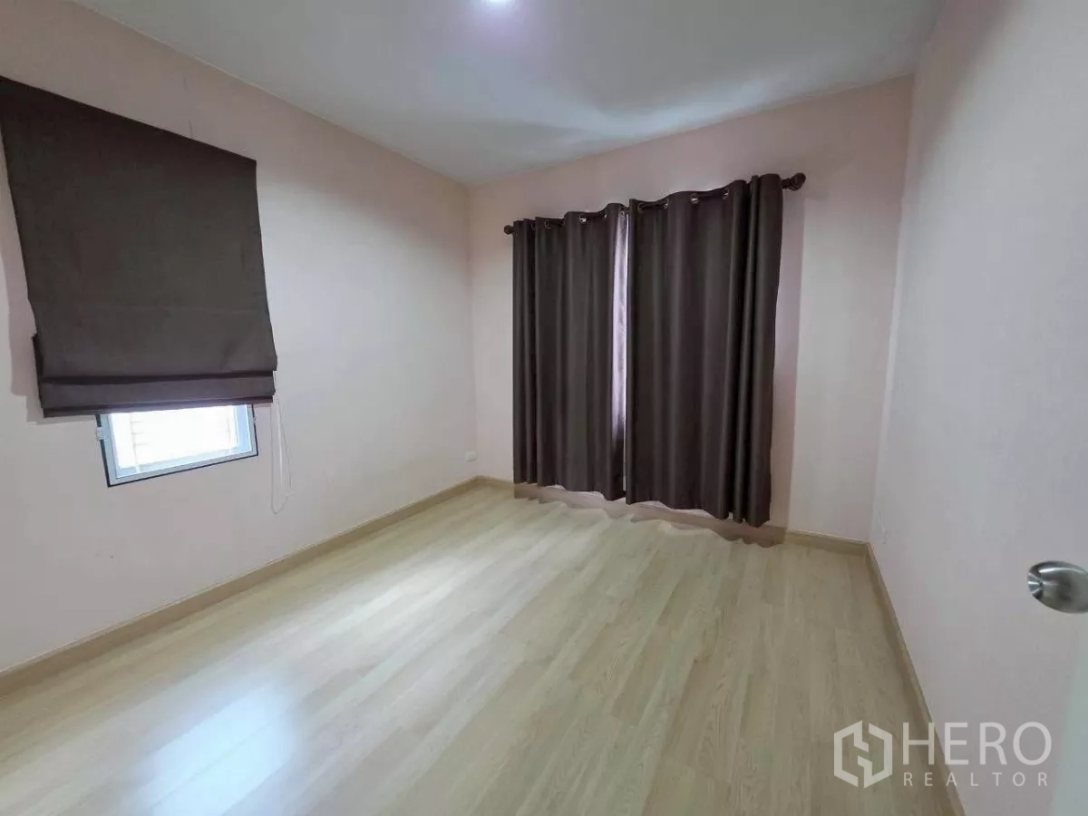 Detached House for rent or sale in Samut Prakan - Third bedroom or flexible room with wood floors and full-height curtains.