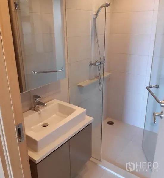 公寓 出租在Khlong Toei, Bangkok - 精致卫生间，方形台盆、镜柜与玻璃淋浴房。