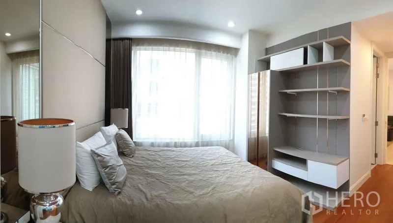 Condominium for rent in Pathum Wan, Bangkok - Spacious master bedroom with built-in shelving and wide windows for natural light.