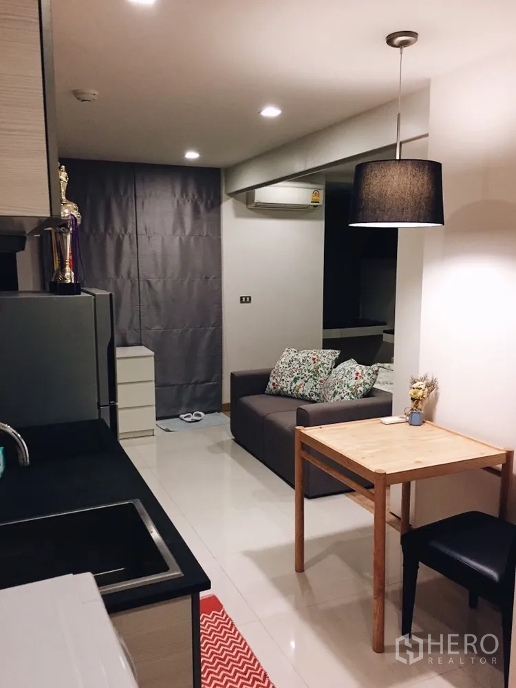 Condominium for rent or sale in Watthana, Bangkok - Open-plan living area with kitchenette, dining table and sofa.