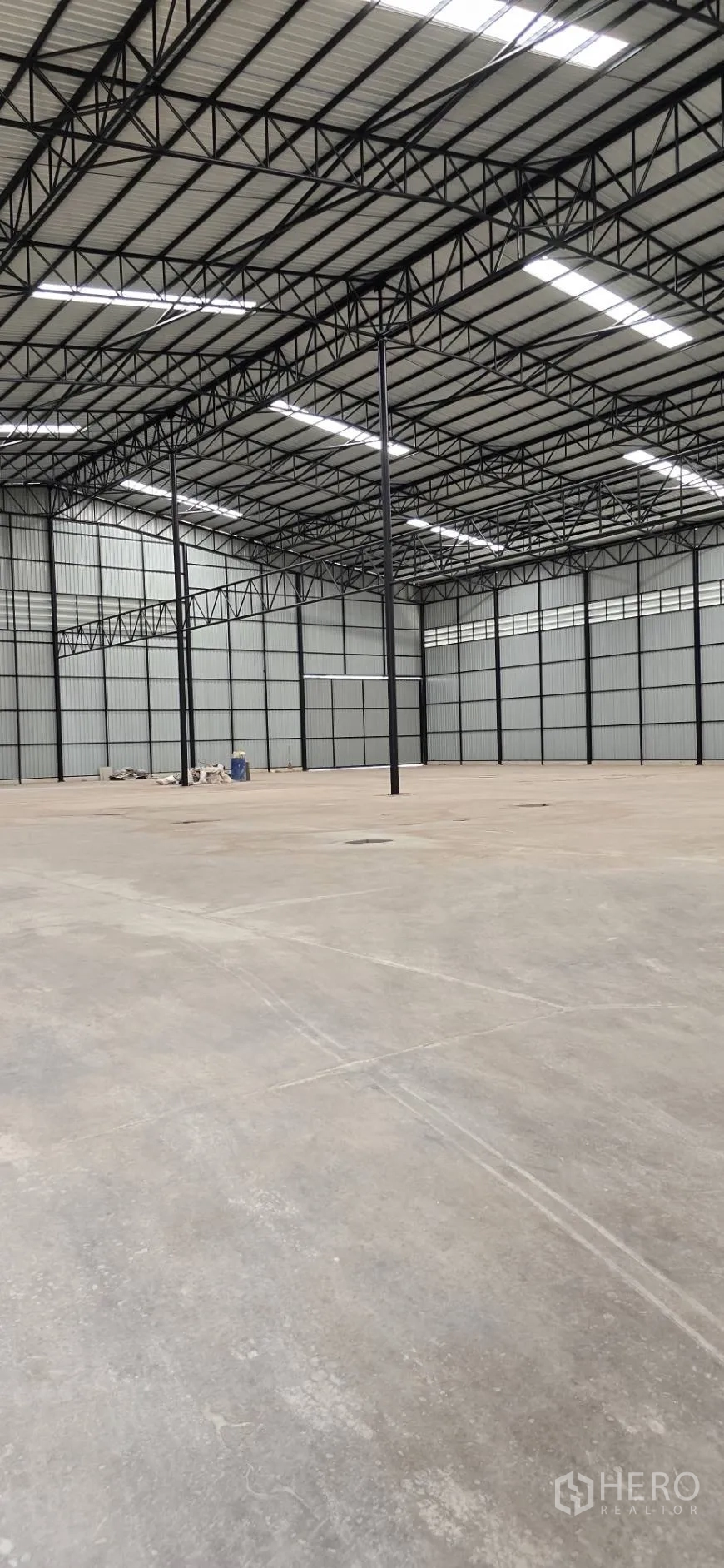 Factory for rent in Mueang Samut Sakhon, Samut Sakhon - Open factory floor showing steel columns, bright roof panels, and smooth concrete surface.