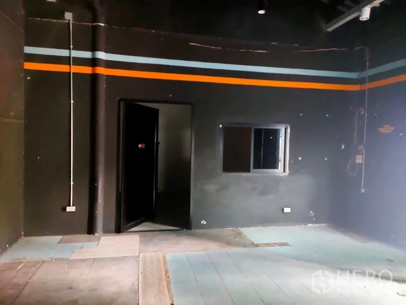 Warehouse for rent in Suan Luang, Bangkok - Interior corner showing a small office room with window and exposed electrical conduits.