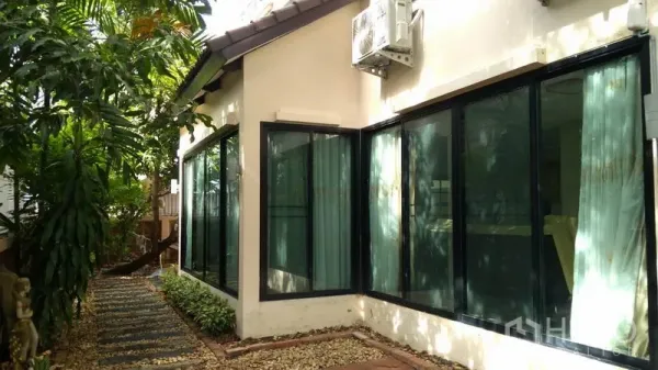 独立式住宅 出租 - 侧院碎石步道，旁有大面积黑框落地窗与空调室外机。