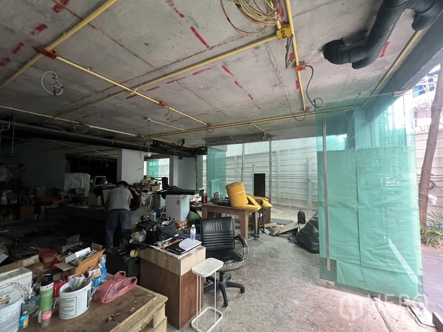 Retail Space for rent - Open-plan retail interior under renovation with desks, exposed services and glass storefront.