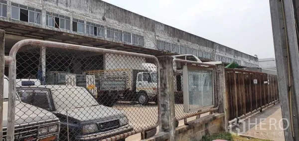 ที่ดิน ขายในLat Krabang, Bangkok - ลานจอดรถบรรทุกภายในรั้ว ข้างอาคารโกดังยาว ในบรรยากาศเขตอุตสาหกรรม