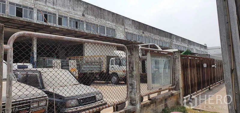 ที่ดิน ขายในLat Krabang, Bangkok - ลานจอดรถบรรทุกภายในรั้ว ข้างอาคารโกดังยาว ในบรรยากาศเขตอุตสาหกรรม