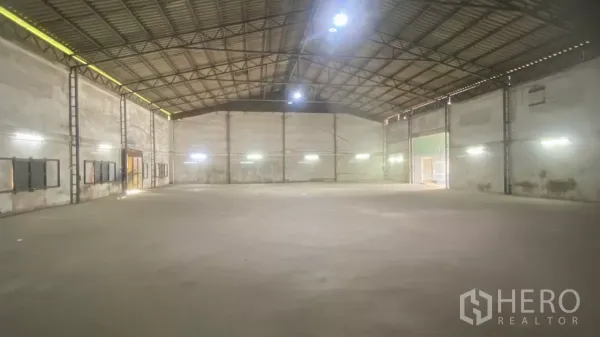 Factory for rent in Bang Sao Thong, Samut Prakan - Open production hall with bright strip lighting, no central columns, and large sliding doors.