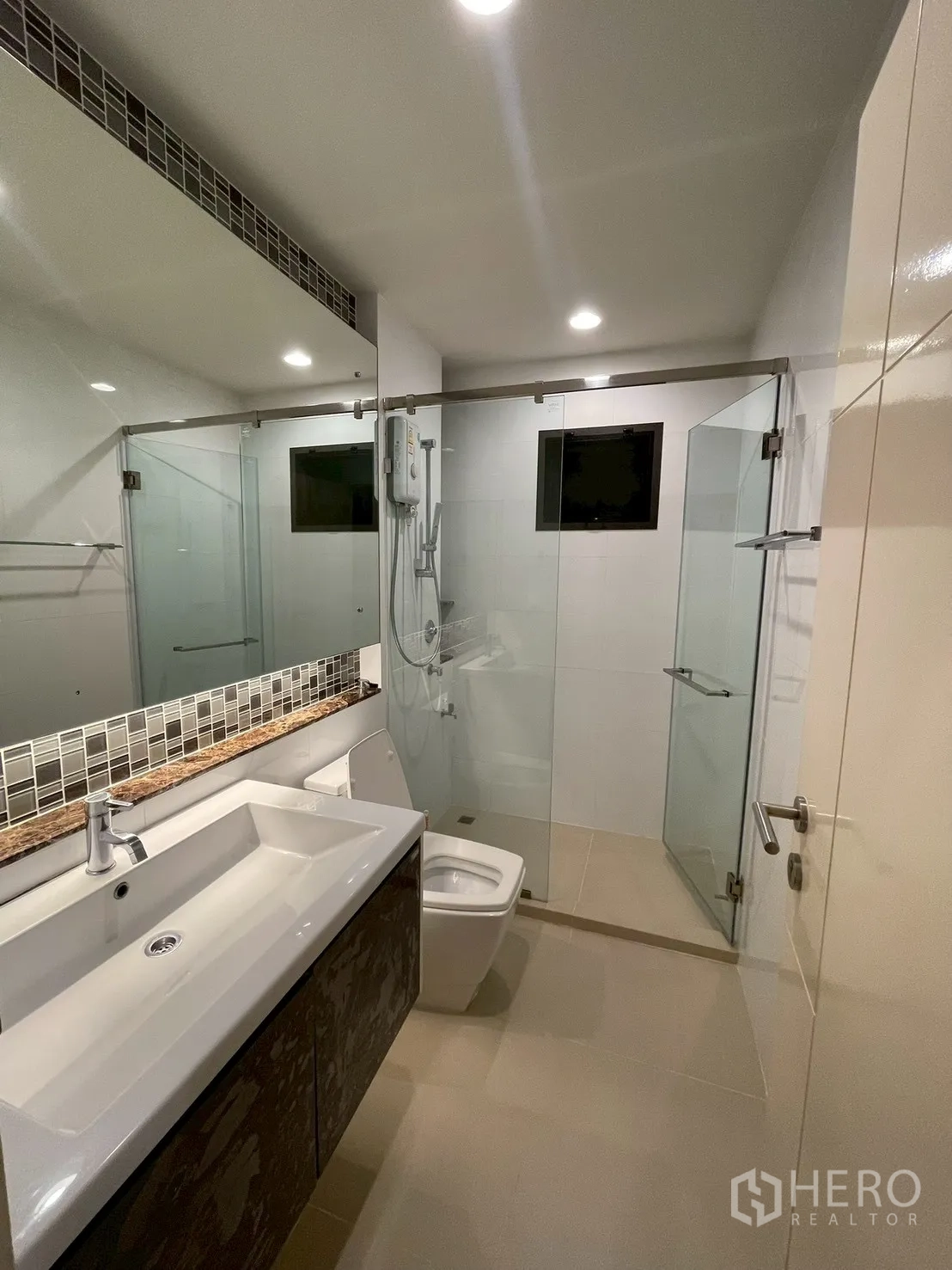 Detached House for rent in Bang Kapi, Bangkok - Bright bathroom with glass shower, long vanity, and toilet.