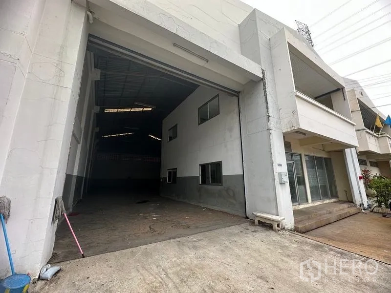 Factory for rent in Khlong Luang, Pathum Thani - Factory façade with wide roller shutter entrance and attached office block.