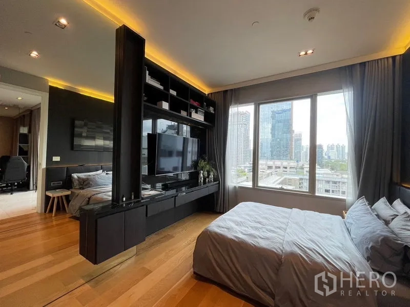 Condominium for rent in Pathum Wan, Bangkok - Bedroom layout with large window, media shelving and partition TV wall.