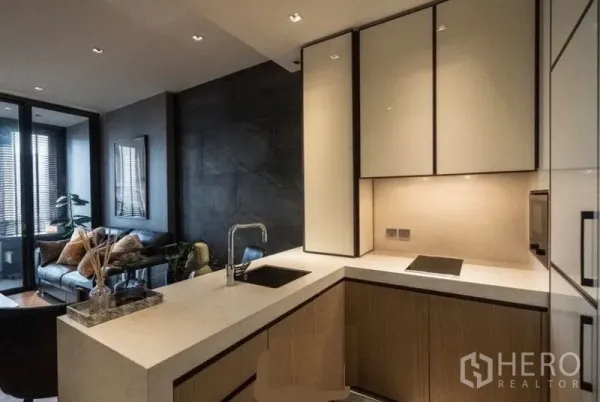 公寓 出租在Khlong Toei, Bangkok - 开放式L形厨房，石材台面与浅色吊柜，连接客厅视野。