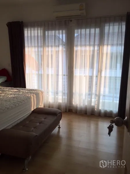 联排别墅 出租或出售在Wang Thonglang, Bangkok - 主卧沐浴阳光，纱帘、阳台门、床与空调一应俱全。