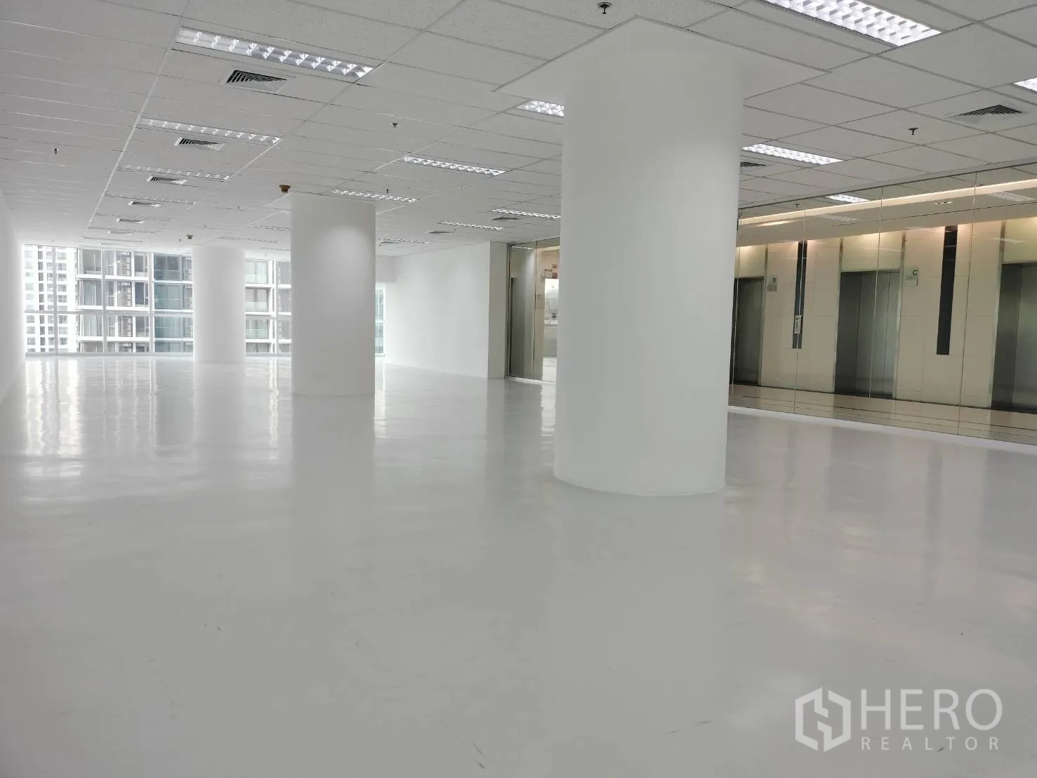 Retail Space for rent in Sathon, Bangkok - Sunlit retail floor with glossy white flooring, columns, and a mirrored elevator lobby wall.