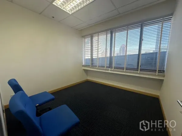 办公空间 出租在Bang Na, Bangkok - 采光良好的办公室角落，蓝色椅子与宽窗可见城市景观。