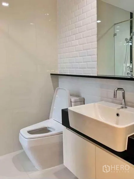 Condominium for sale in Ratchathewi, Bangkok - Contemporary bathroom with white tiles, square basin and glass shower.