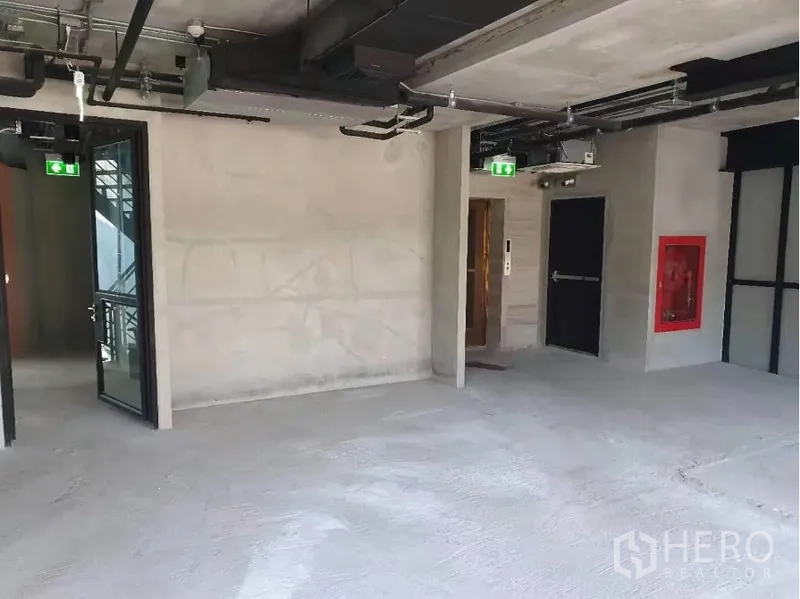 零售空间 出租在Khlong Toei, Bangkok - 未装修零售楼层，开放式天花，电梯门与消防栓柜。