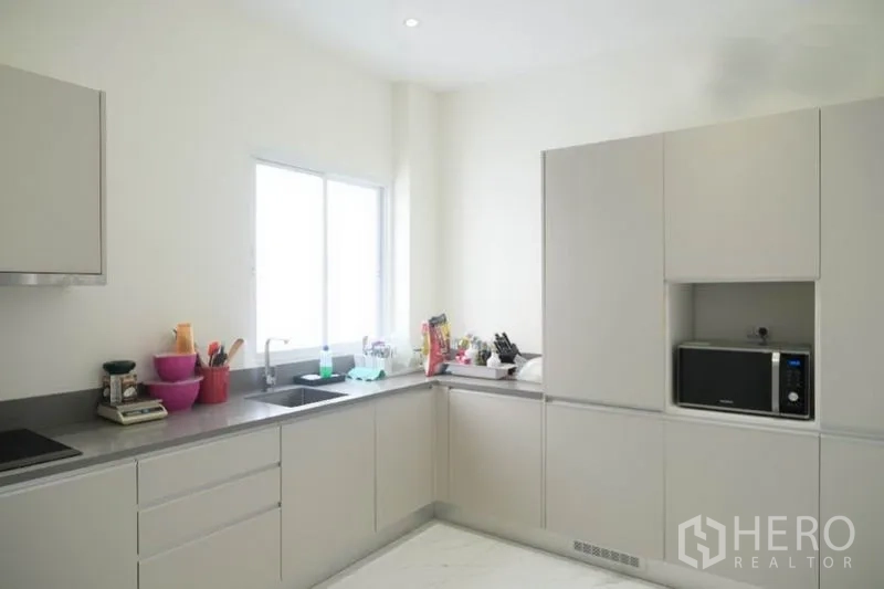 Home Office for rent or sale in Prawet, Bangkok - Minimalist kitchen close-up showing built-in cabinets, cooktop and microwave niche.