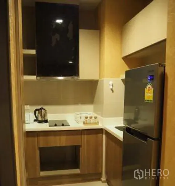 Condominium for rent in Sathon, Bangkok - Compact fitted kitchen with cooktop, hood, cabinets and stainless refrigerator.