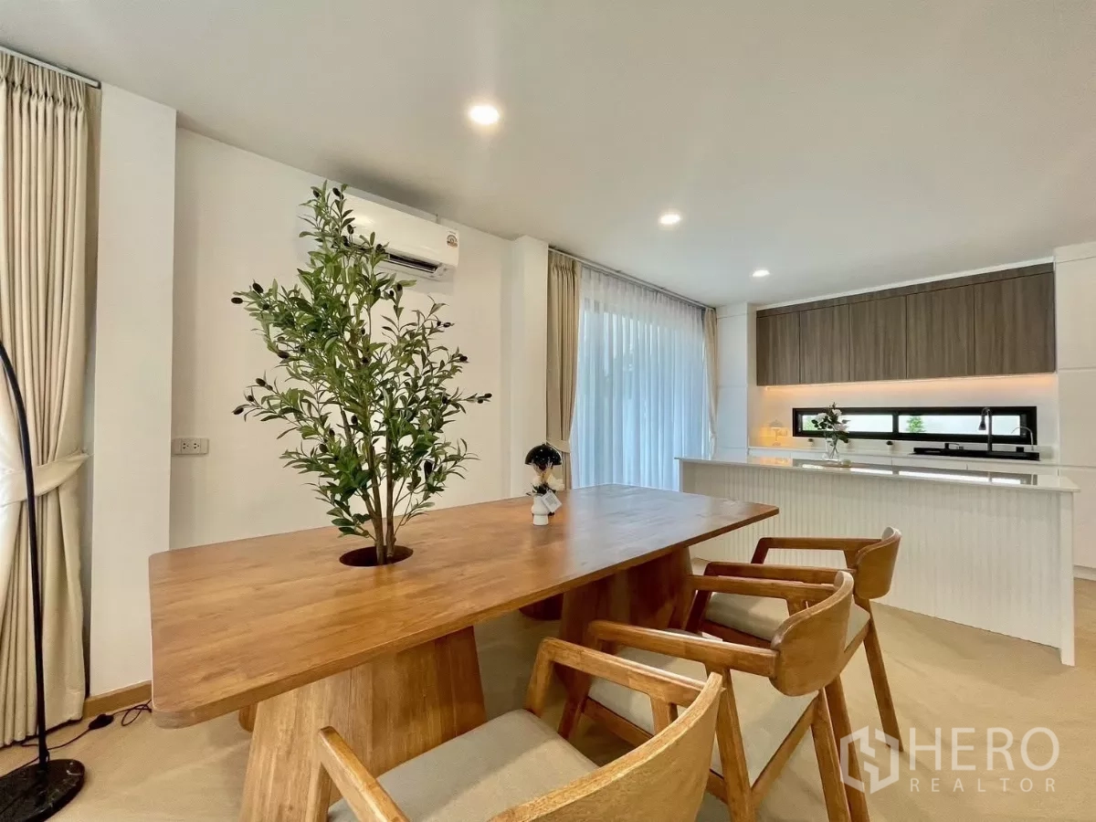 独立式住宅 出售在Prawet, Bangkok - 餐区配木质长桌和椅子，连接开放式厨房。