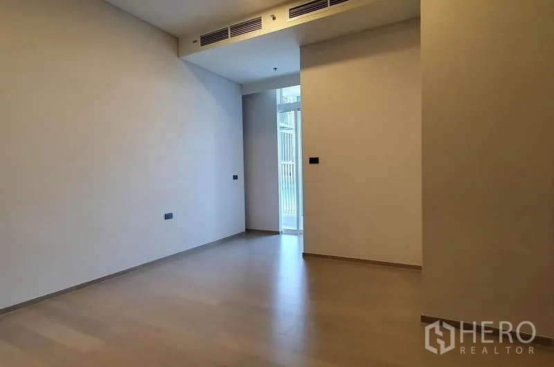 Condominium for sale in Khlong Toei, Bangkok - Spacious bedroom with ducted air-conditioning and a door to the balcony or service area.