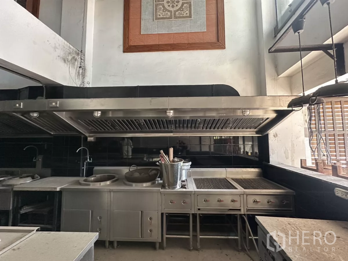 店屋 出租在Bang Na, Bangkok - 不锈钢炒灶、烤台与大型排烟罩的近景。