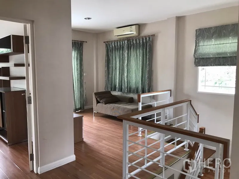 Detached House for rent in Khlong Sam Wa, Bangkok - Second-floor landing with daybed, windows and white stair railing.