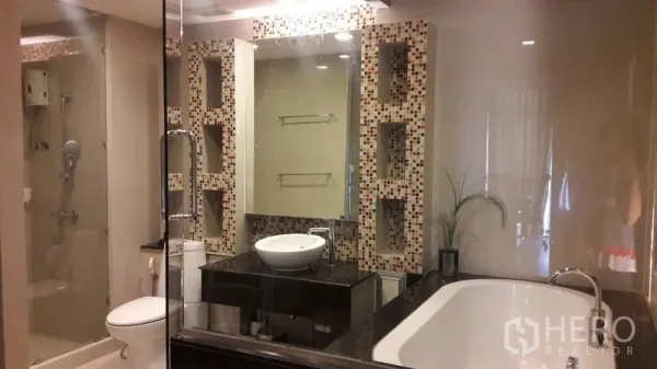 Condominium for rent in Khlong Luang, Pathum Thani - Contemporary bathroom with glass shower, bathtub, vessel sink and a mosaic feature wall with niches.