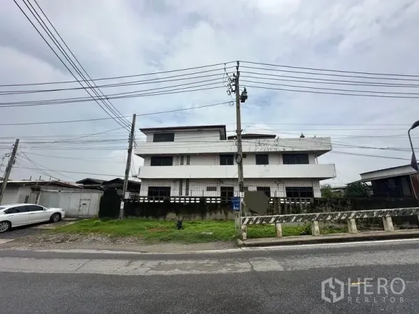 Home Office for sale in Phra Pradaeng, Samut Prakan - Street-front view of a three-storey white home office building with power lines in Phra Pradaeng.