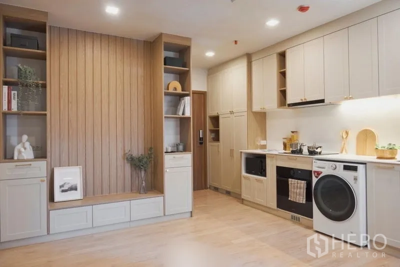 Condominium for sale in Suan Luang, Bangkok - Open-plan view showing built-in shelving and a full linear kitchen.
