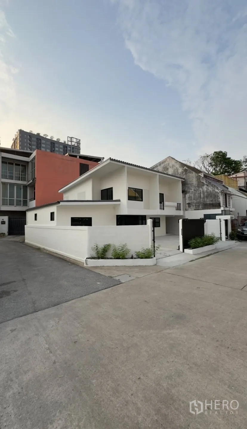 Detached House for rent in Suan Luang, Bangkok - Corner exterior of a newly renovated white two-storey detached house with walled frontage and driveway.