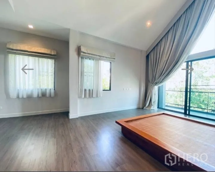 Detached House for sale in Saphan Sung, Bangkok - Master bedroom with large windows, balcony view, wood floors and drapes.