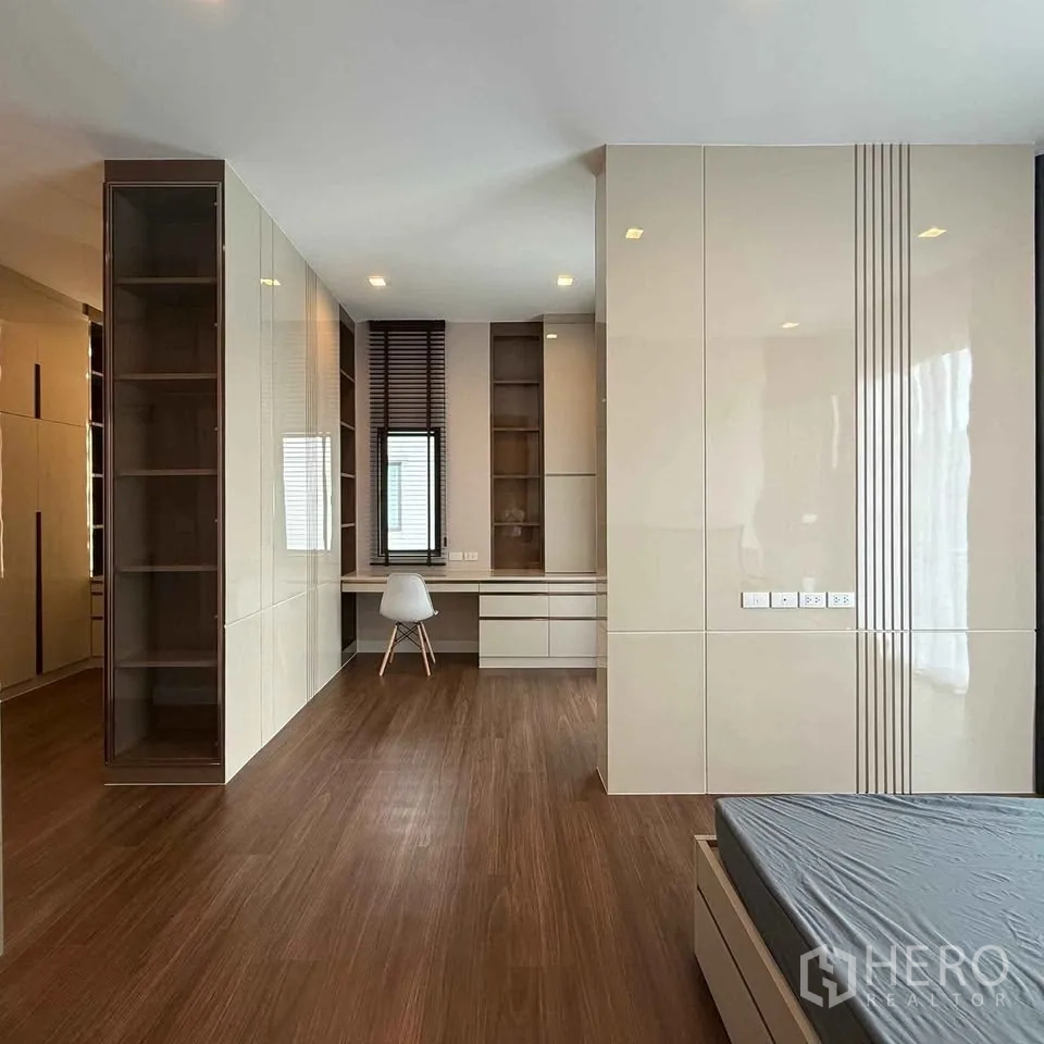 Detached House for rent in Bang Phli, Samut Prakan - Spacious bedroom with wood floors, long study nook and open shelving.