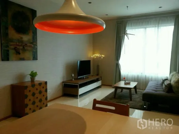 公寓 出租或出售在Khlong Toei, Bangkok - 明亮的客厅，大窗、灰色沙发、电视柜与醒目吊灯。