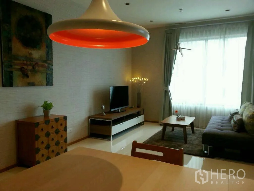 公寓 出租或出售在Khlong Toei, Bangkok - 明亮的客厅，大窗、灰色沙发、电视柜与醒目吊灯。