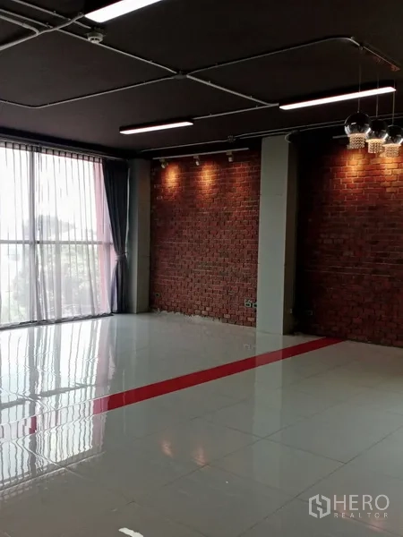 办公空间 出租在Khlong Toei, Bangkok - 办公室一角，红砖装饰墙、宽窗与吊灯相映成趣。