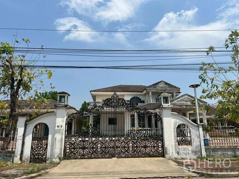 Detached House for rent in Prawet, Bangkok - Front facade behind a decorative iron gate and white fence.