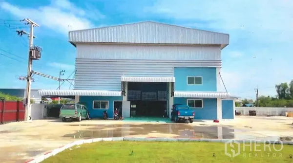 工厂 出售在Lat Lum Kaeo, Pathum Thani - 工厂正立面，蓝灰色金属外墙，宽大卷闸门与停车场