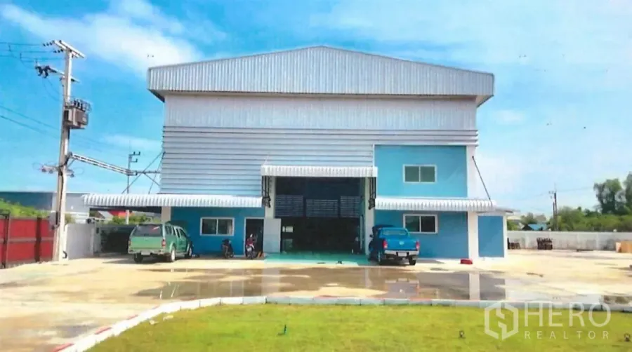 โรงงาน ขายในLat Lum Kaeo, Pathum Thani - ภาพด้านหน้าของโรงงานสีฟ้าเทา ประตูม้วนขนาดใหญ่และลานจอดกว้าง