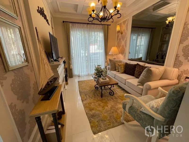 Detached House for rent or sale in Pathum Thani - Cozy living room with chandelier, sofa set, TV console and sheer curtains.