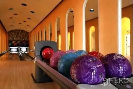 Condominium for rent in Khlong Toei, Bangkok - Colorful bowling balls lined up on a lane in a private bowling alley with warm lighting.