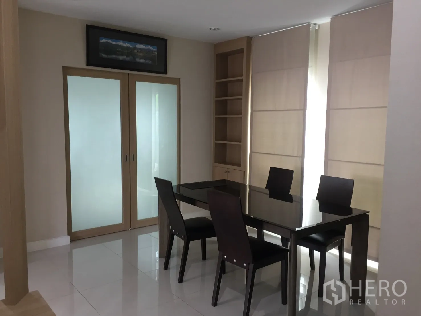 Detached House for rent in Pathum Thani - Dining room with a glass-top table, four chairs, built-in shelves and large windows.