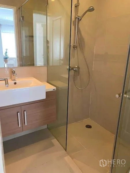 คอนโด ให้เช่าในBangkok - ห้องน้ำปูกระเบื้องโทนครีมพร้อมตู้กระจกกั้นอาบน้ำแบบวอล์กอินและอ่างล้างหน้า